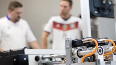 In the foreground one can see the motors with which the AI plays table soccer. In the background are two human players.