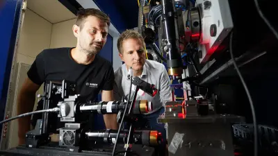 Specialists monitor a laser-based testing process at an analysis facility.