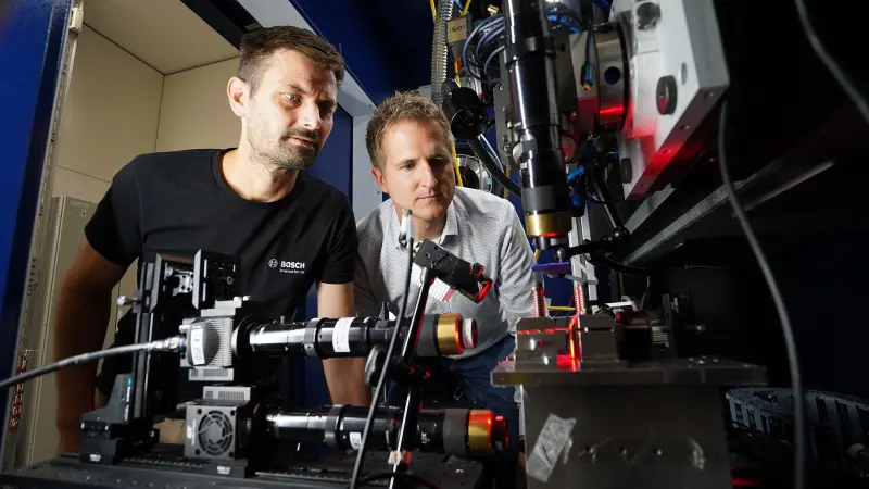 Specialists monitor a laser-based testing process at an analysis facility.