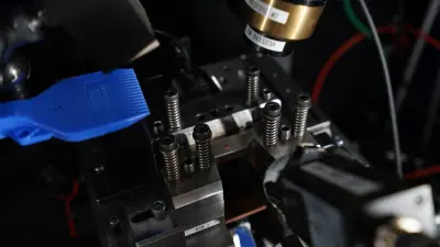 Laser measurement system examines a metal sample in a high-precision testing setup.