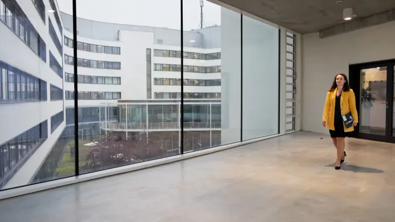 Isabel läuft mit Laptop unter dem Arm durch einen Gang.