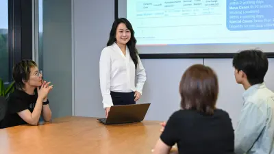 Jessica präsentiert eine Folie in einem Meeting mit ihrem Team.