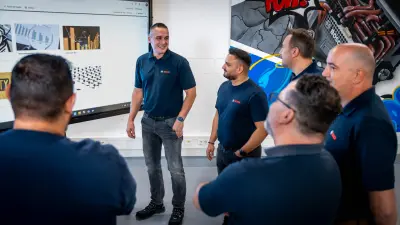 Mario macht mit seinem Team eine Besprechnung vor einem Bildschirm.