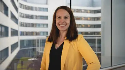 Isabel trägt einen gelben Blazer und lächelt in die Kamera.