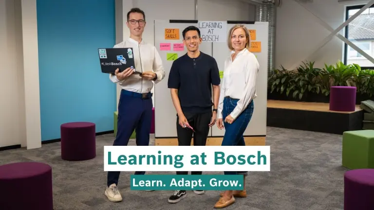 Hamza, Antonio and Karolina stand in front of a workshop board covered with sticky notes.