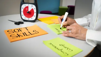 A clock, a pair of scissors and several sticky notes lie on the table. One of them says: Soft skills.