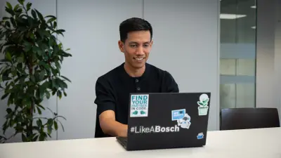 Antonio works on his laptop and smiles.