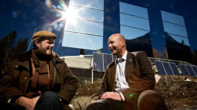 The image shows two residents of Rjukan in front of a heliostat.