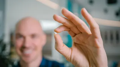 Benjamin, who can be seen out of focus in the background, holds a semiconductor chip up to the camera.