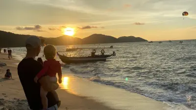 Benjamin carries his daughter and enjoys the sunset with her in Malaysia.