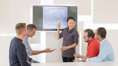 Kejia Wang bespricht etwas mit Kollegen aus ihrem Team.