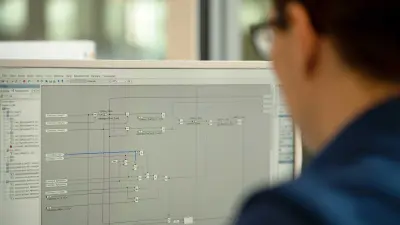Michael Huis Schulter und Hinterkopf sind angeschnitten zu sehen. Er ist zu einem Computerbildschirm gewandt. Der Bildschirm ist im Fokus, darauf sind Linien und Zahlen zu sehen.
