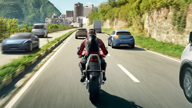 Back view of a motorcyclist riding on a two-lane road.