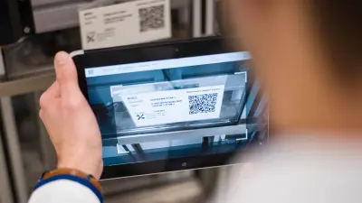An employee at the Bosch plant calls up a machine manual with a QR code on a tablet.