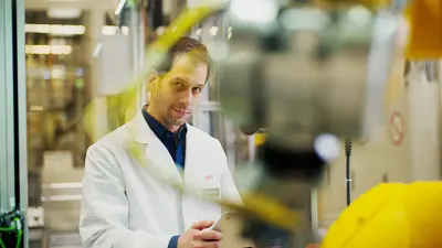 Industry 4.0 technician Tobias Richter checks the status of a machine in the manufacturing plant on his tablet.