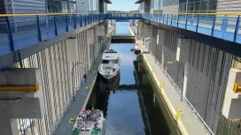 Boat in a ship lift chamber, with walkways and bridges on both sides.