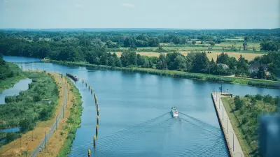 Waterway with a boat, navigation posts and green landscape viewed from above.