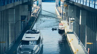 Large boat and smaller boats inside a narrow water chamber surrounded by concrete structures.