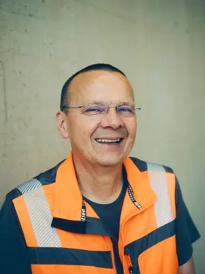 Portrait of a person wearing glasses and an orange high-visibility vest