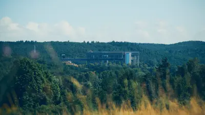 Ship lift structure visible in the distance beyond dense green trees and grass.