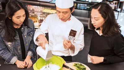 Connie Lv with a cook and another woman in the show kitchen of Bosch's flagship store.