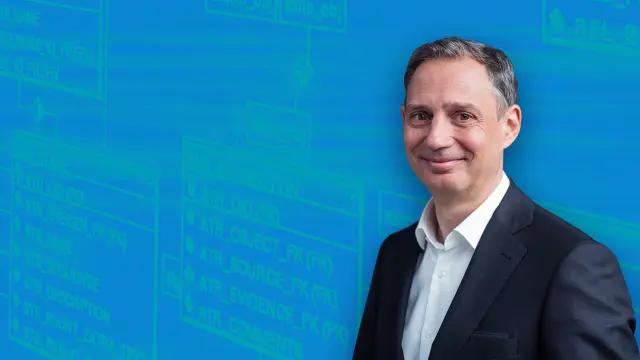 Jörg Dederichs in front of a blue wallpaper.