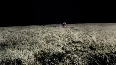 In a wide-angle perspective, employees are seen at night in the field. The vastness of the field where the alien emoji will take shape is clearly visible.