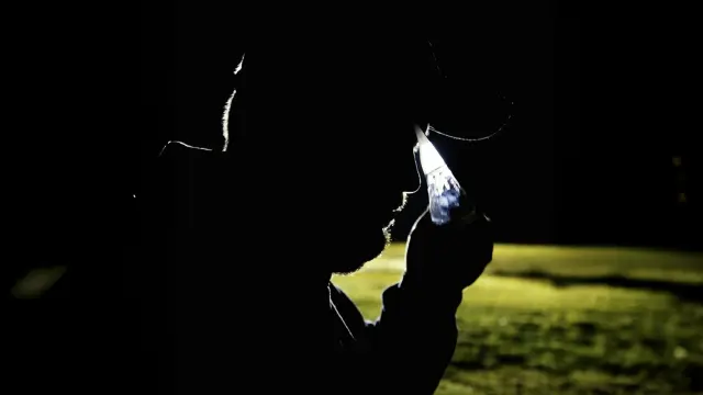 A man in a dark environment puts on safety goggles. The lighting creates a mystical atmosphere, indicating that something exciting is about to happen.