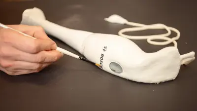 A hand blender made of cake is precisely painted with a brush to emphasize details.