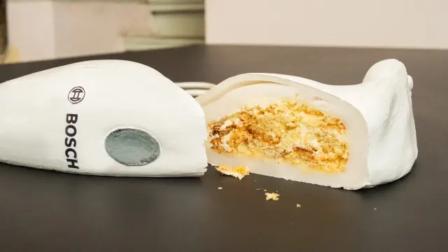 A cut cake in the shape of a Bosch hand blender.