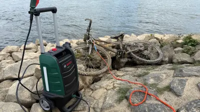 Bosch Hochdruckreiniger neben schmutzigem Fahrrad am Flussrand.