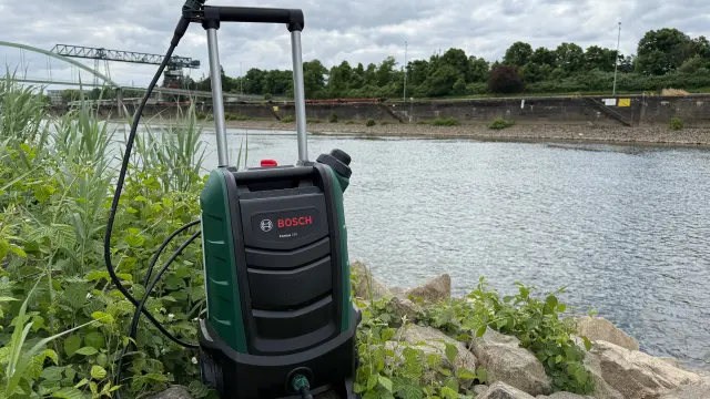 Bosch Hochdruckreiniger steht am Rande des Rheins im Grünen.