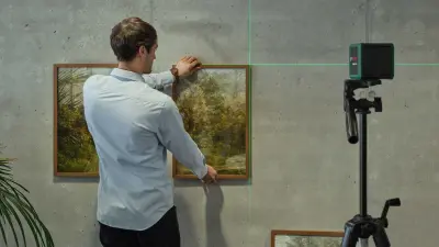 With the help of the Quigo Green cross-line laser, Simon Kalt hangs a framed picture on the wall.