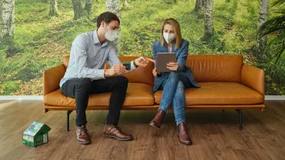 Isabelle Gola and Simon Kalt sit on a sofa and look at a tablet computer. Next to them lies the packaging of the Quigo Green.