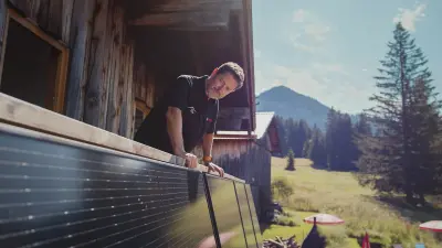 Reiner steht auf dem Balkon seiner Berghütte und begutachtet seine Balkon-Solaranlage.