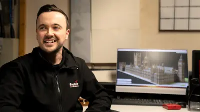 Mann sitzt in einem Raum vor einem Computer-Bildschirm mit Abbildung des Westminster-Palastes.