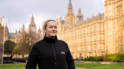Blonde Frau steht vor dem Westminster-Gebäude in London.