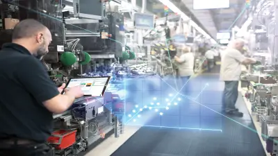 Employee holds a tablet in an industry 4.0 factory together with other employees.