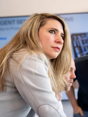 Person leaning forward in discussion in front of a presentation screen.