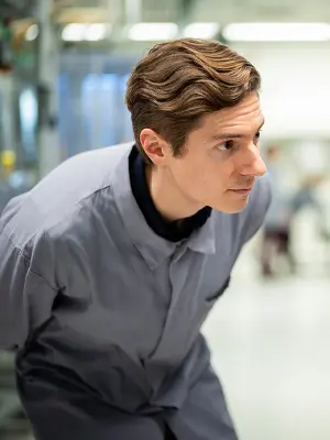 Person in work clothing leaning forward in an industrial environment.