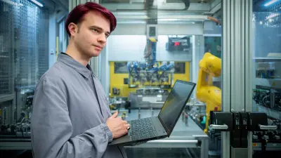 Two people in work coats talking inside a production area.