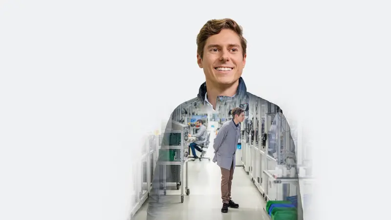 Person in workwear standing in a production hall between automated machines.