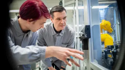 Two people in work coats inspecting equipment in a production cell.