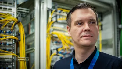 Person standing in front of network cabinets with yellow cables.