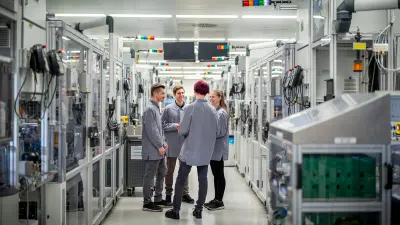 Group of people standing in a corridor between production machines.