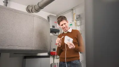 Martin Weiss is in a basement and checks the energy manager. This software solution is integrated in the Bosch Smart Home Controller.