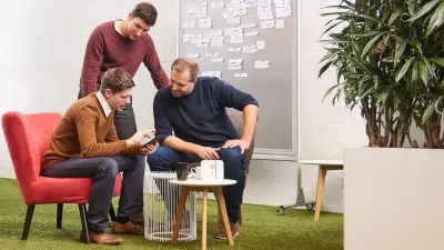 Martin Weiss has a meeting with two colleagues and shows them the app of the energy manager.