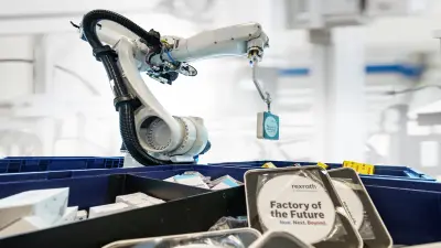 Zu sehen ist der Roboterarm des Smart Item Picking Systems umgeben von Kisten mit kleinen Gegenständen in der Modellfabrik von Bosch Rexroth in Ulm.