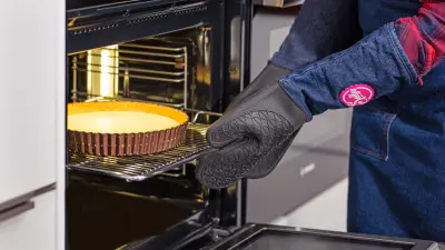 Die Food-YouTuberin Sally Özcan holt mit Backhandschuhen eine Zitronentarte aus dem Sensor-Backofen der Serie 8 accent line von Bosch.