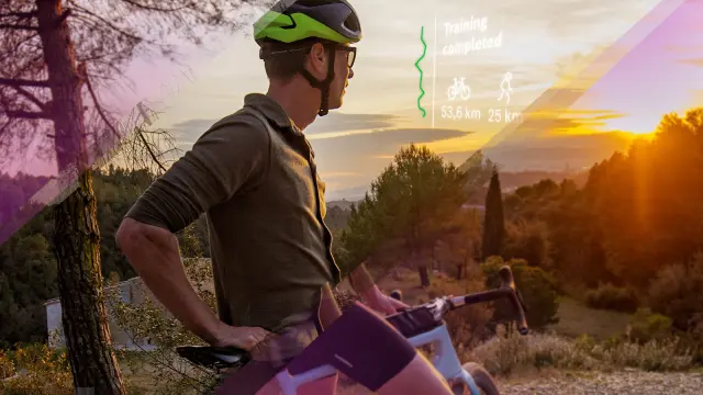 Eine Person mit Fahrrad und Fahrradhelm blickt durch eine smarte Brille und sieht die Einblendung seiner Trainingsleistung.